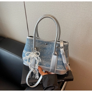 Detailsicht der Jeans-Beuteltasche mit silbernen Spiegelpaneelen und Perlen-Spitzenschleife