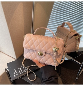 Detailed close-up of pink quilted crossbody bag with gold chain and ball charm