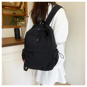 Detail of black nylon travel backpack with red label showing side pocket and zipper features