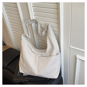 Detail of minimalist beige nylon hobo bag with adjustable wide strap on black surface