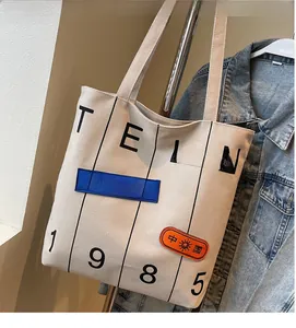 Detail of canvas tote bag featuring vintage graphic prints and woven patches