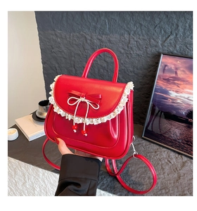 Dettaglio di borsa rossa in pelle con bordo in pizzo bianco e ciondoli di perle