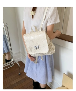 Creamy white lace backpack with silver butterfly clasp shown in a lifestyle daily scene