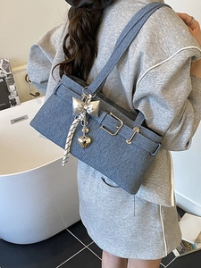 Blue denim texture tote bag with metallic buckle and charms shown from a 45-degree angle
