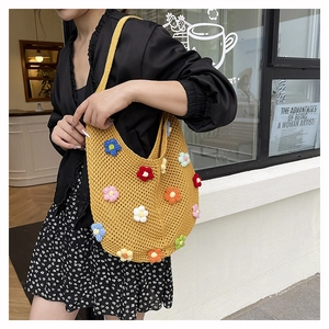 Detail of yellow knit crochet tote bag featuring 3D multicolored flower appliques