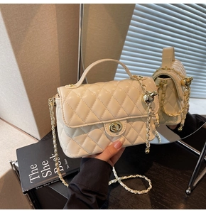 Detail of cream quilted bag showing golden turn-lock, chain strap and mirror reflection