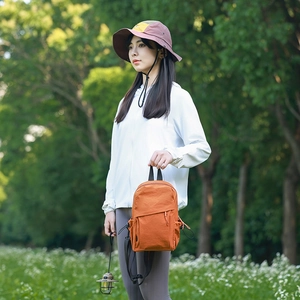 Detail of an orange canvas mini backpack and color-block outdoor sun hat in a park