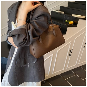 Detail of dark brown lychee pattern leather tote bag carried on woman's shoulder