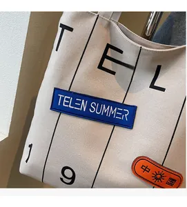 Detail of off-white canvas tote bag with TELEN SUMMER embroidery and durable texture