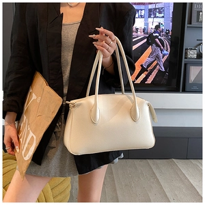 Close-up of beige lychee-pattern leather tote bag shown in a professional urban styling