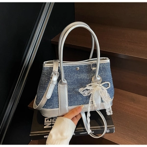 Detailansicht der gepunkteten Denim-Tasche mit silbernem Griff und Perlen-Spitzen-Anhänger