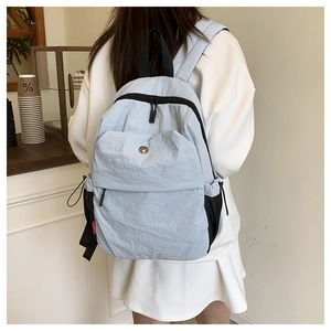 Detail of light blue nylon backpack with dual zippers and adjustable mesh side pockets