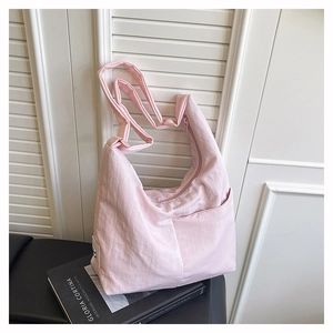 Close-up of light pink hobo bag with pleated nylon fabric against a minimalist background