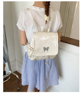 Détail du sac à dos crème avec broderie papillon et fermoir métallique argenté au dos