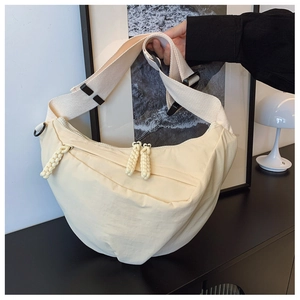 Dettaglio borsa a mezzaluna beige in tela con tirazip intrecciati e tracolla larga in tessuto