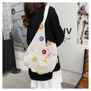 Close-up of a white hand-knitted tote bag featuring colorful 3D crochet floral details