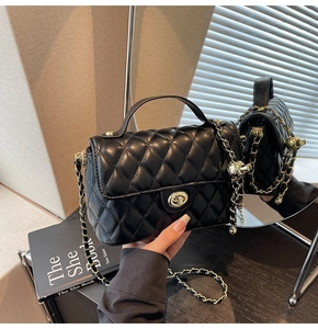Detail of black quilted leather handbag with gold metal twist lock and chain strap