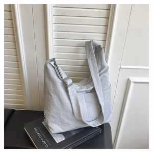 Detail of grey nylon tote bag with adjustable strap and buckle on a book background
