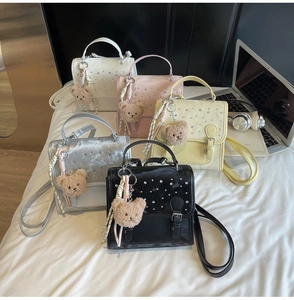 Detail view of colorful faux leather handbags with sparkling rhinestone flap and plush bear charm