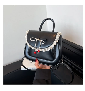 Dettaglio borsa in pelle nera con pizzo bianco e ciondoli con perline rosse