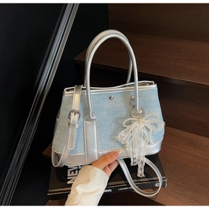 Detailansicht der hellblauen Pailletten-Eimertasche mit silbernem Lederbesatz und Perlenbogen