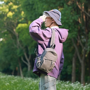 Outdoor scene showing a gray lightweight waterproof sling bag worn by a person in a forest