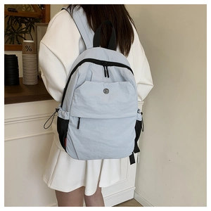 Detail view of light blue nylon backpack with multiple pockets and adjustable black straps