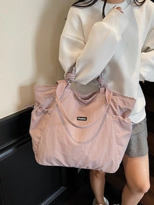 Pink nylon tote bag with fashion label and drawstring pockets shown on a model shoulder