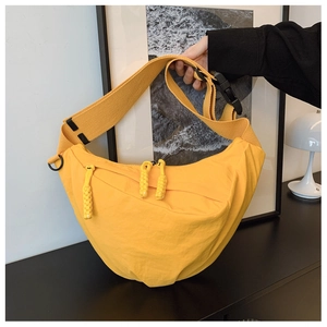 Dettaglio di una borsa a mezzaluna in nylon giallo brillante con ampia tracolla in tessuto