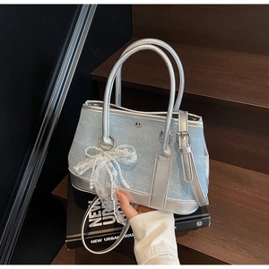 Details der hellblauen Denim-Beuteltasche mit Glitzer-Finish und Perlen-Spitzen-Schleife