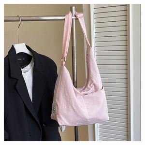Detail of light pink nylon hobo bag featuring side pocket and refined metal logo