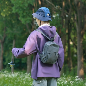 Close-up of a durable dark grey nylon outdoor backpack worn by a model in nature