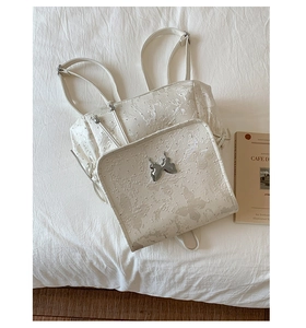 Détail de la broderie papillon sur tissu jacquard blanc avec boucle en métal argenté