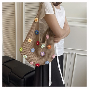 Detail of colorful 3D crochet flowers on a handmade khaki knit shoulder tote bag