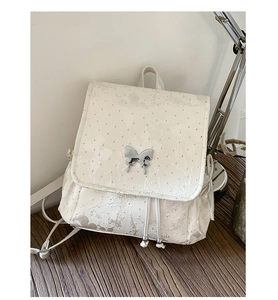 Close-up of white butterfly backpack showing embossed texture and silver metal charm