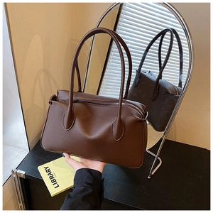 Detail of dark brown lychee textured leather tote with metal zipper and long handles