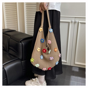 Detail of hand-crocheted hollow tote bag with colorful 3D floral accents for beach use