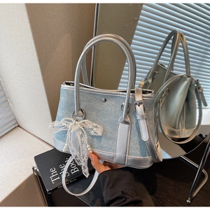 Detail der Jeans-Eimertasche mit silbernem Lederbesatz, Strass und Spitze-Schleife