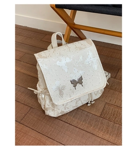 Détail d'un sac à dos beige perlé avec broderie papillon et boucle en métal dorée