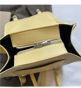 Close-up of the pale yellow bag interior with silver metal zipper and inner compartments