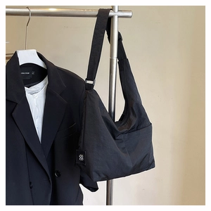 Detail view of a large black nylon tote bag hanging with a blazer for a business casual look
