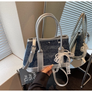Detail der Beuteltasche aus silbernem Metallic-Leder und Denim mit Perlen-Spitzenschleife