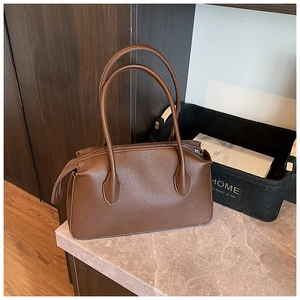 Detail view of brown lychee texture leather tote bag with silver zipper on marble table