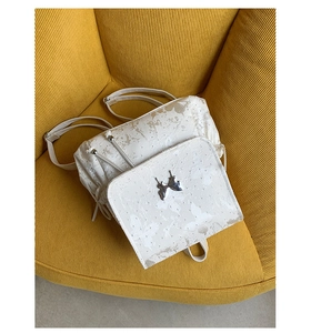 Détail du sac à dos blanc avec imprimé papillon et ornement papillon en métal argenté