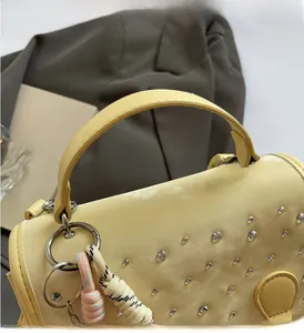 Detail of yellow leather handbag with rhinestone studs and colorful woven rope charm