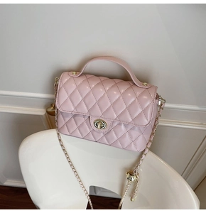 Detailed view of pink quilted handbag with gold chain strap and turn-lock closure