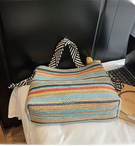 Top view of a colorful striped woven tote bag with geometric patterned handles on a desk
