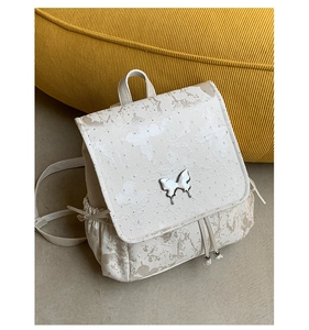 Vue détaillée de la broderie papillon et boucle argentée sur sac à dos crème stylé