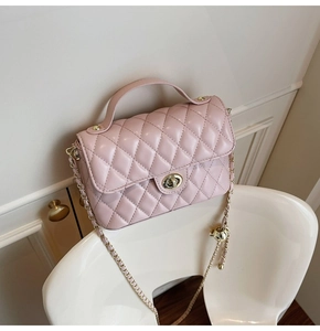 Close-up of pink quilted faux leather handbag with gold metal clasp and chain strap