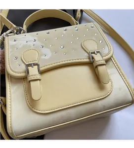 Detail of cream yellow crossbody bag featuring silver rhinestones and premium fabric